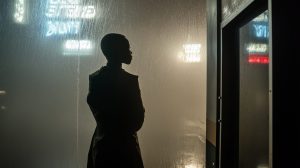 A woman is looking out the rainy window